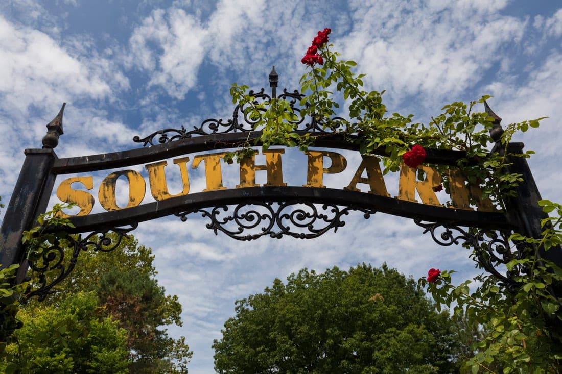The wrought iron South Park entrance arch, with gold lettering reading South Park and climbing roses growing over the gate.